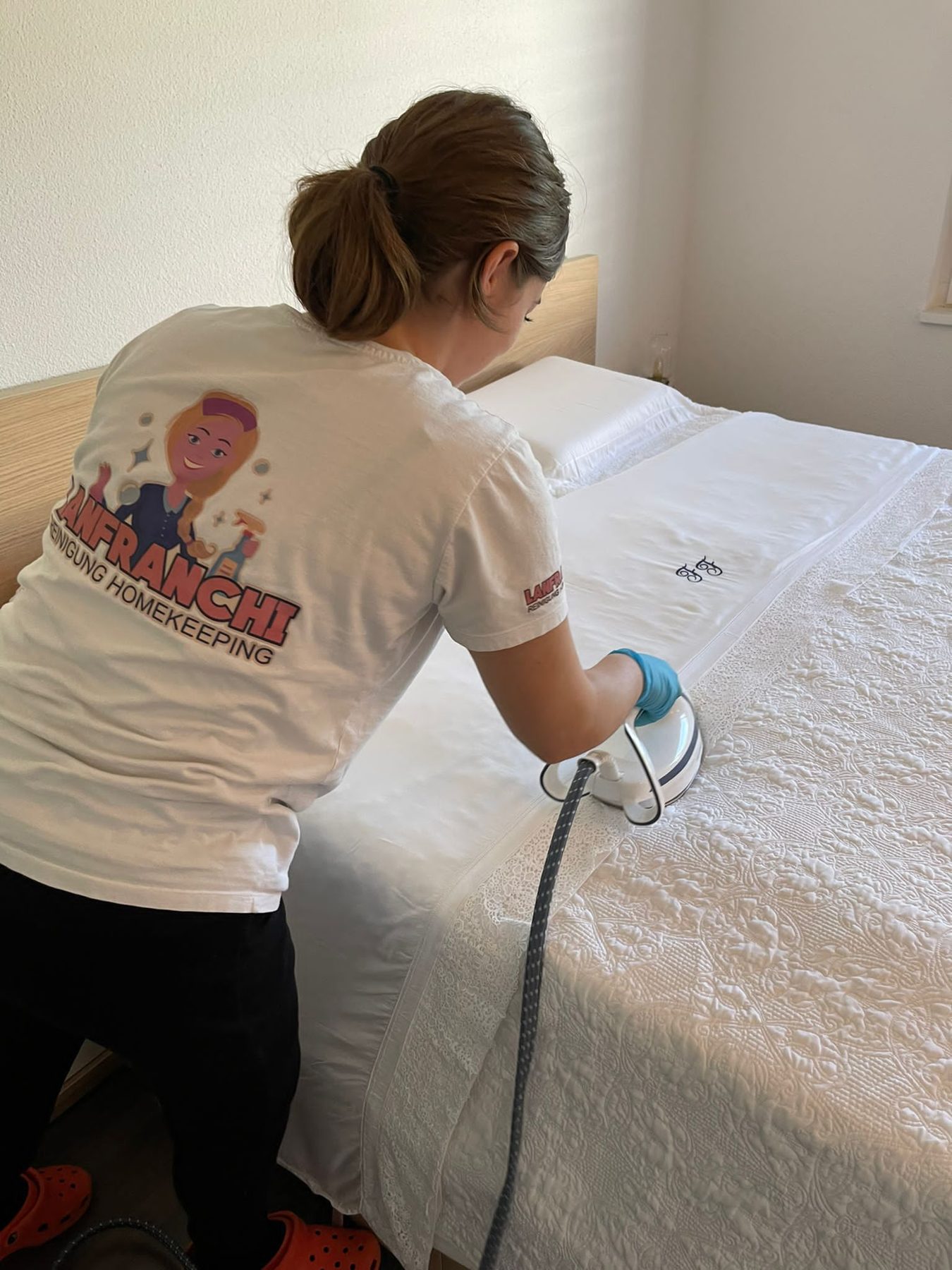 Mitarbeiterin in Lanfranchi-Shirt dämpft ein Bett mit dem Dampfgerät